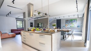 Una cocina moderna con una isla central, electrodomésticos integrados y un comedor con un amplio ventanal.