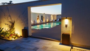 Un área de piscina exterior moderna con sillas de descanso y un sendero bien iluminado.