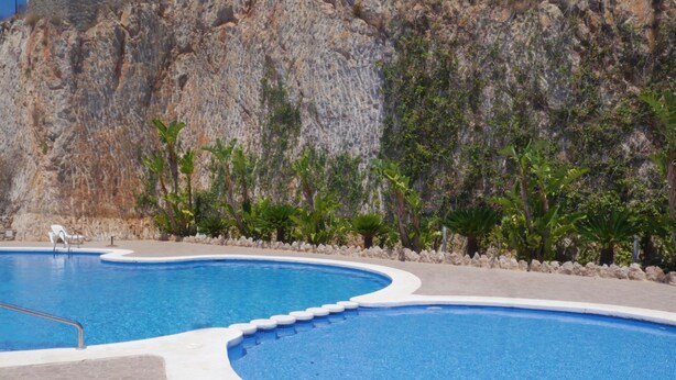 Une piscine à bordures courbes et une terrasse dallée de pierres.
