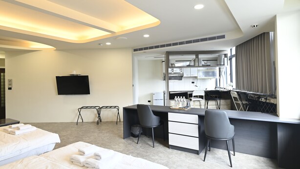 Een moderne hotelkamer met een bed, bureau en kitchenette.