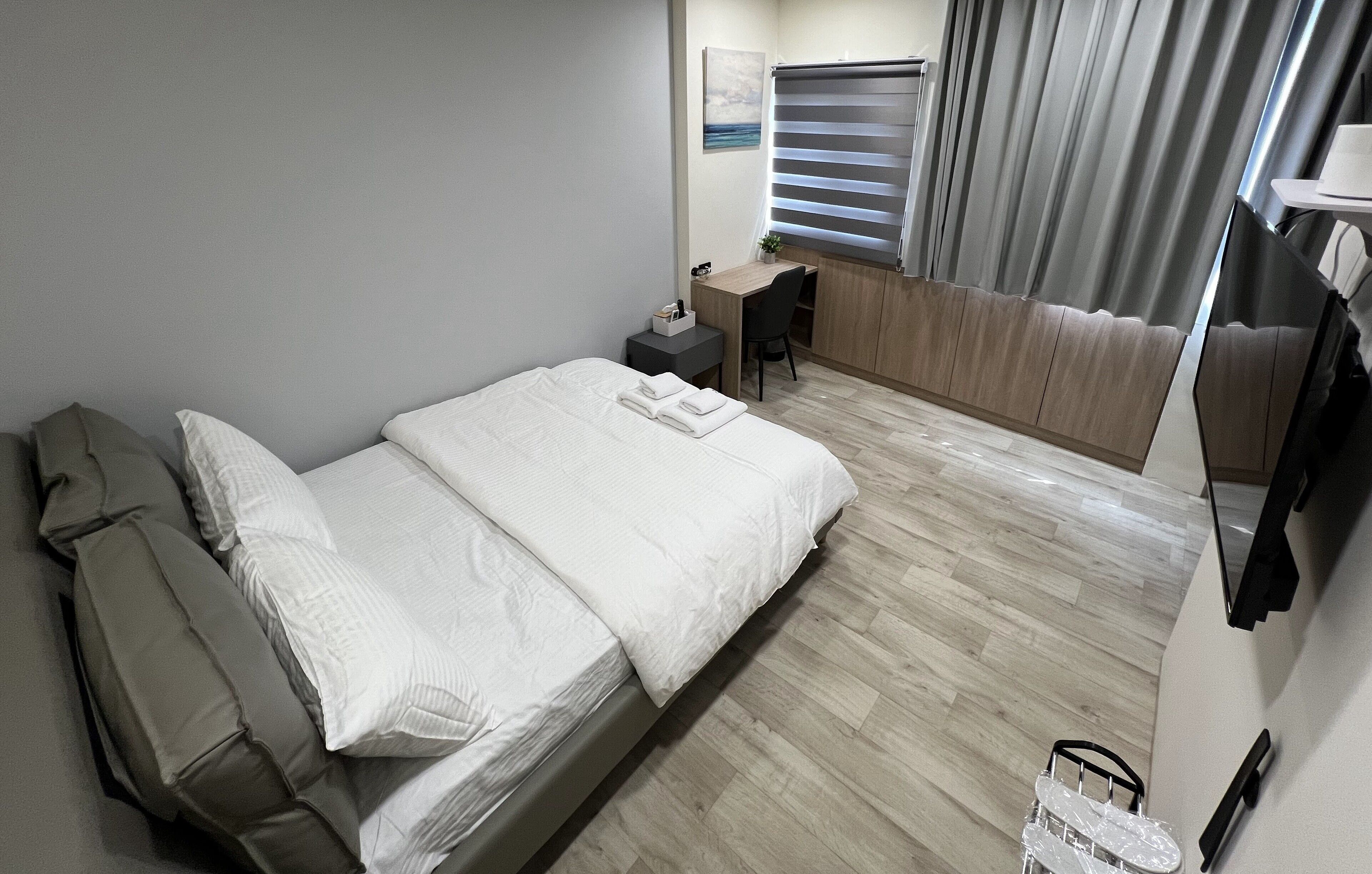 Una habitación de hotel moderna con cama, escritorio y televisor.