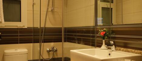 A modern bathroom with a glass-enclosed shower, a white toilet, and a sink with toiletries.