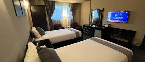 A hotel room with two beds, a desk, a chair, a television, and a mirror.