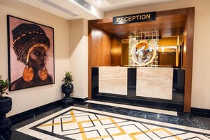A reception area with a wooden reception desk, a large framed artwork on the wall, and a geometric patterned floor.