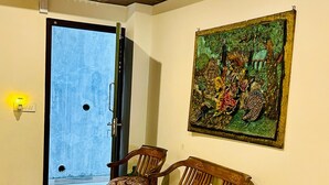 Un pasillo con piso de madera, una puerta que da al exterior y un cuadro colgado en la pared.