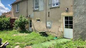 Un edificio a due piani con facciata vissuta, diverse finestre e un piccolo giardino antistante.
