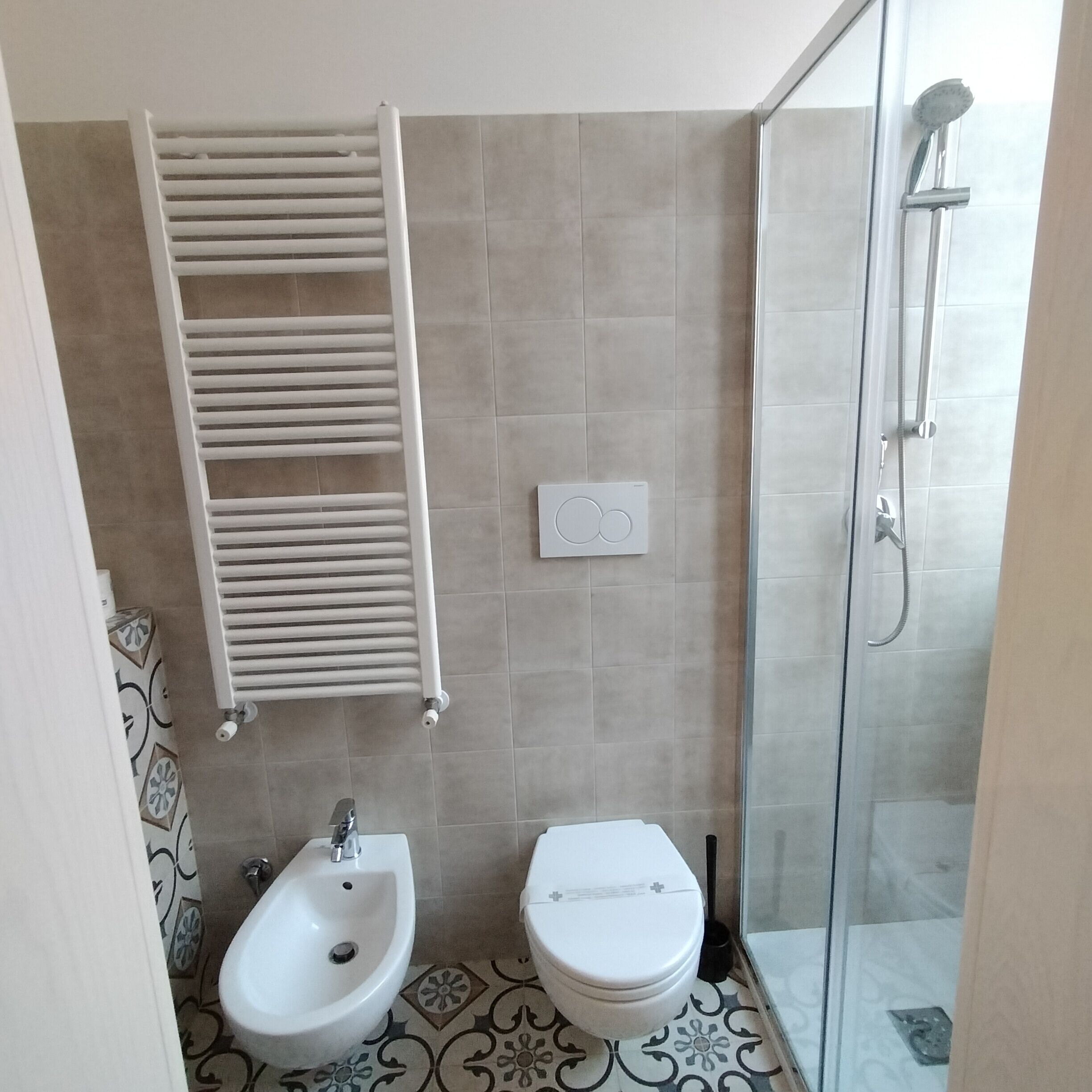 Un baño con bidé, inodoro, ducha y toallero.