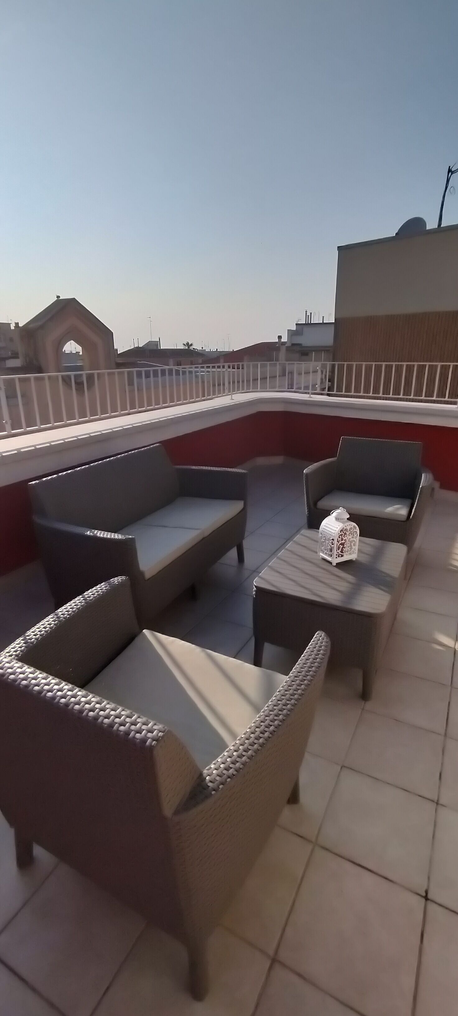 A rooftop terrace with wicker furniture and a white lantern.