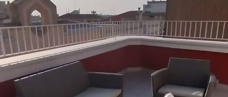 A rooftop terrace with wicker furniture and a white lantern.