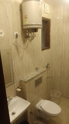 A bathroom with a toilet, sink, and a water heater mounted on the wall.