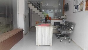 An office with a reception desk, a computer, and a chair. There is a staircase in the background. - Hotel Nue-Nest (Rishikesh)