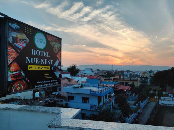 A billboard advertising Hotel Nue-Nest with a contact number and location details.