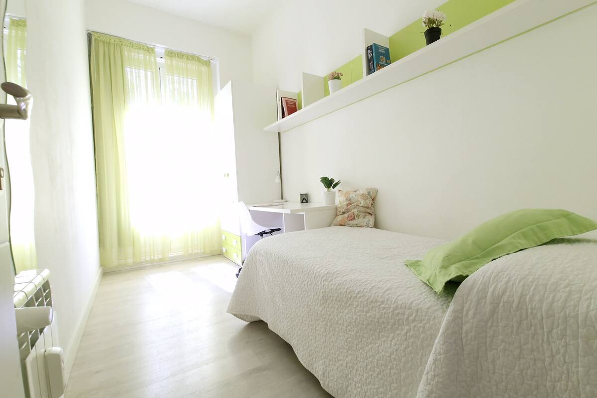 Une chambre à coucher avec un lit, un bureau et une étagère contenant des livres et une plante.