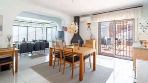 A spacious living room with a dining area, a fireplace, and a view of the outside.