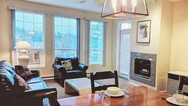 Una sala de estar con chimenea, una mesa de comedor para dos personas y un sofá.