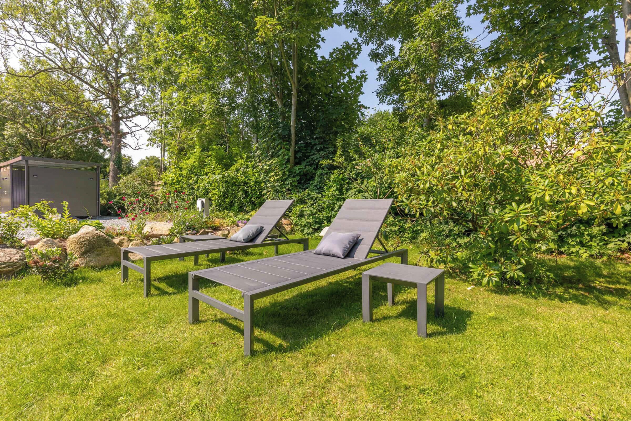 Ein Garten mit zwei Liegestühlen und einem kleinen Gartenhaus.