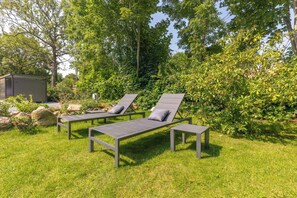 Un jardin avec deux chaises longues et un petit abri de jardin.