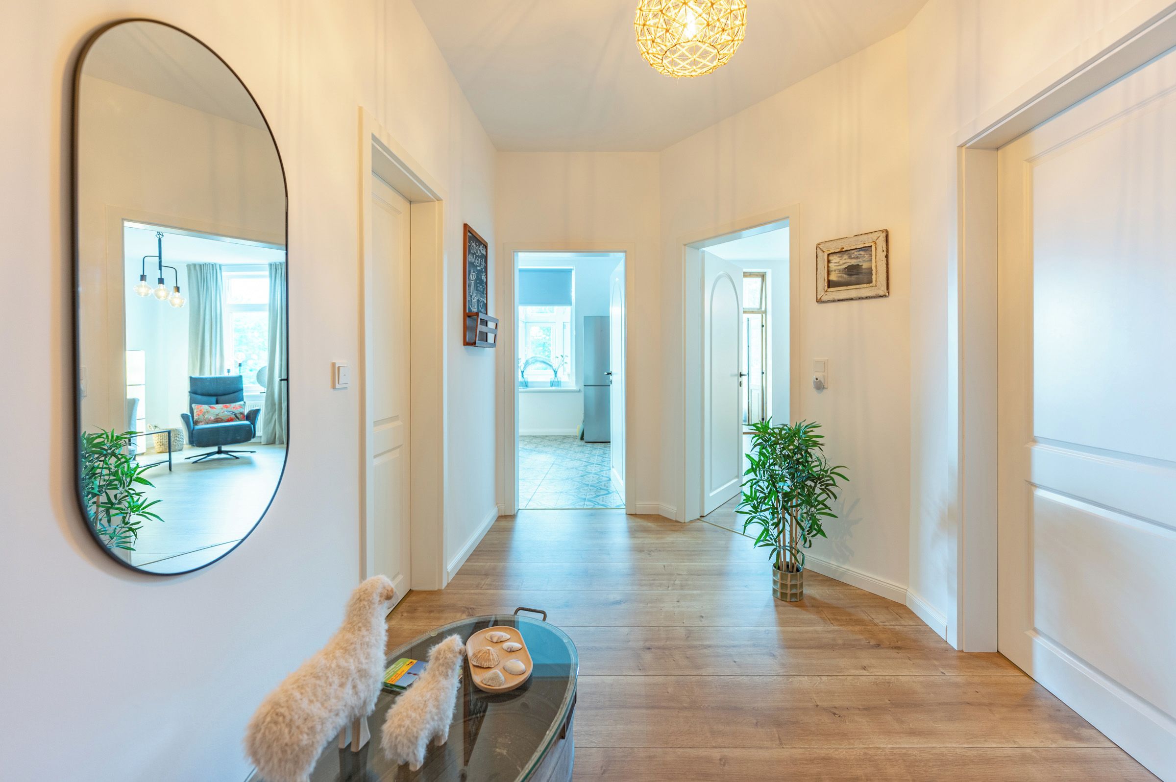 A hallway with a round mirror, a dog, and a tray with seashells.