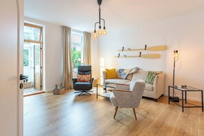 Een moderne woonkamer met een bank, fauteuils, een salontafel en een vloerlamp.