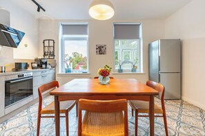 A modern kitchen with a dining table, chairs, and a refrigerator.
