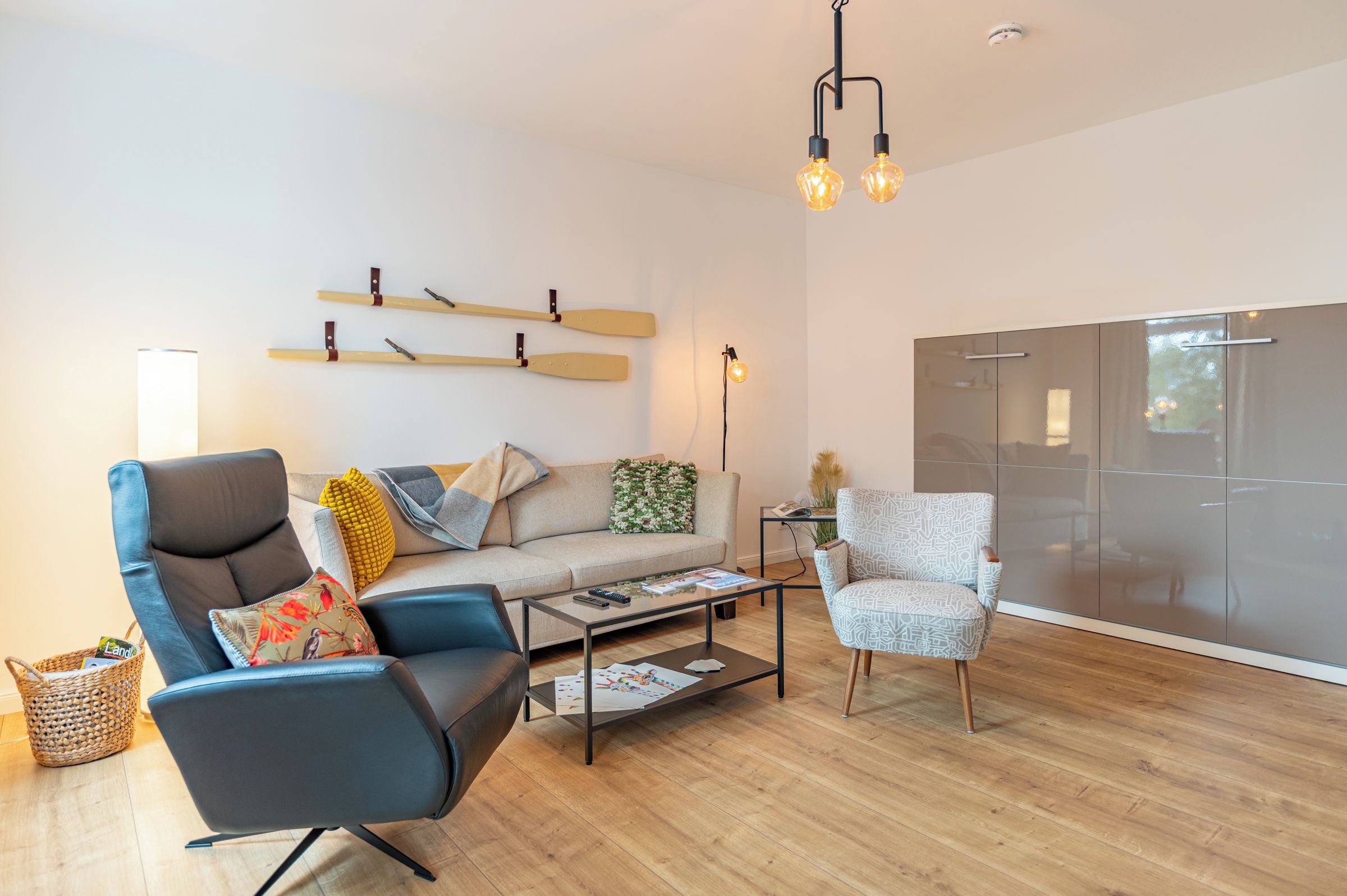 Ein modernes Wohnzimmer mit einer Couch, zwei Sesseln, einem Couchtisch und einer Vitrine.
