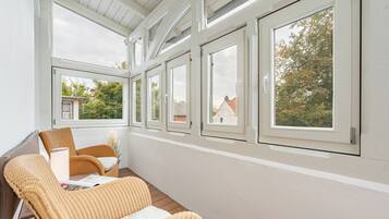 A sunlit room with a wooden floor, white walls, and a row of windows.