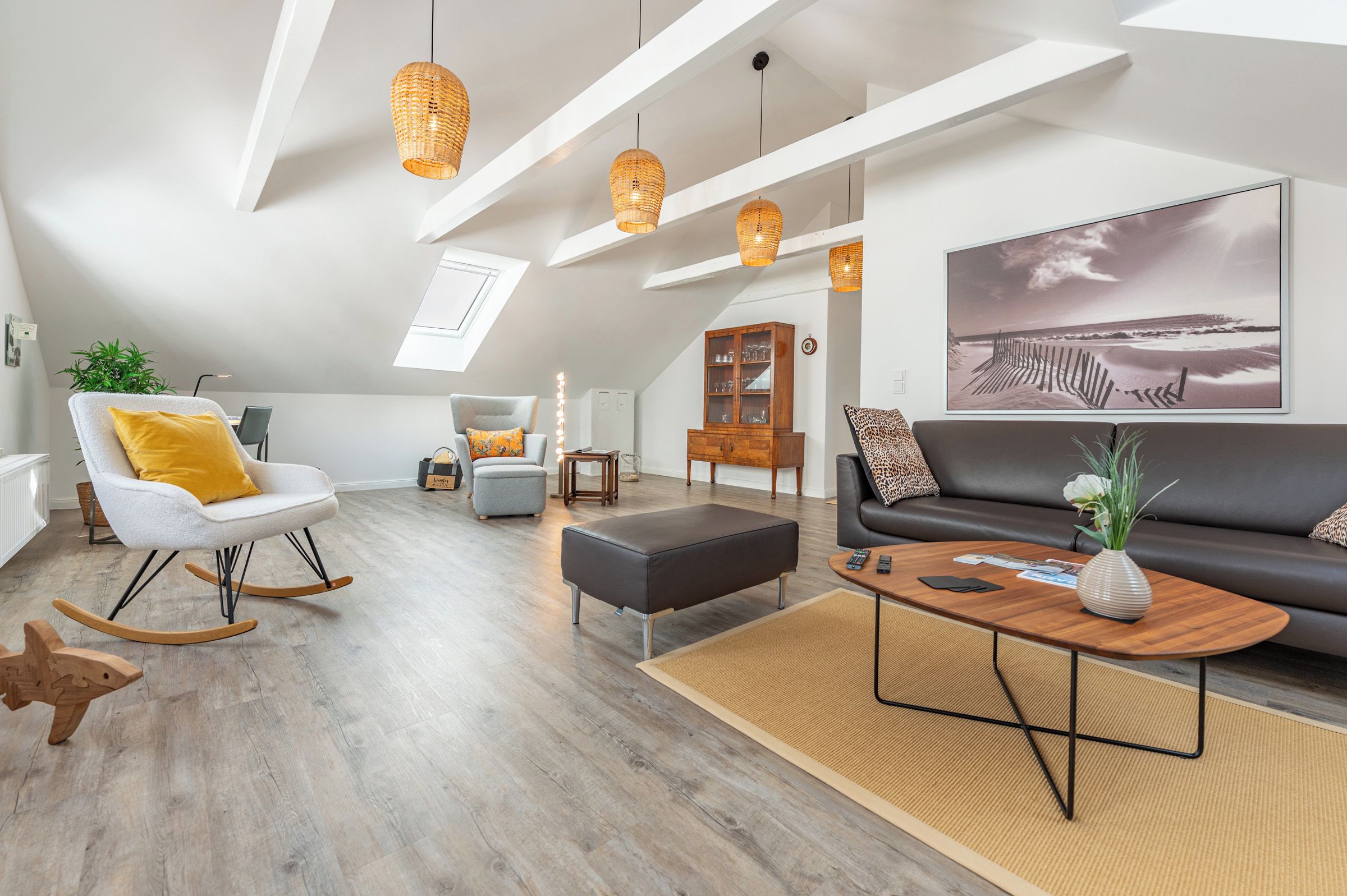 Un loft espacioso con techo alto, vigas a la vista y un tragaluz grande.