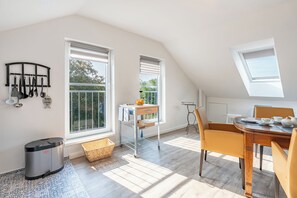 A bright kitchen with a dining area, large windows, and a view of greenery. - Die Ferienwohnung "gretes Dackstuuv" in Garding für bis zu 4 Personen (Garding)
