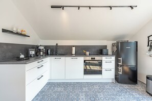 Une cuisine moderne avec des meubles blancs, un réfrigérateur noir et un four encastré.