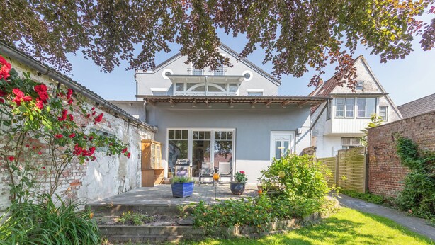 A two-story house with a front porch, a small garden, and a brick wall on the left. - Die Ferienwohnung "gretes Dackstuuv" in Garding für bis zu 4 Personen (Garding)