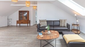 A modern loft apartment with a dark leather sofa, a wooden coffee table, and a skylight. - Die Ferienwohnung "gretes Dackstuuv" in Garding für bis zu 4 Personen (Garding)