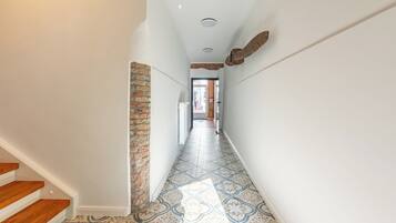 Un pasillo con piso estampado, pared de ladrillo decorativa y escalera de madera.