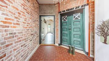 Un pasillo con paredes de ladrillo y una puerta verde con diseño decorativo.