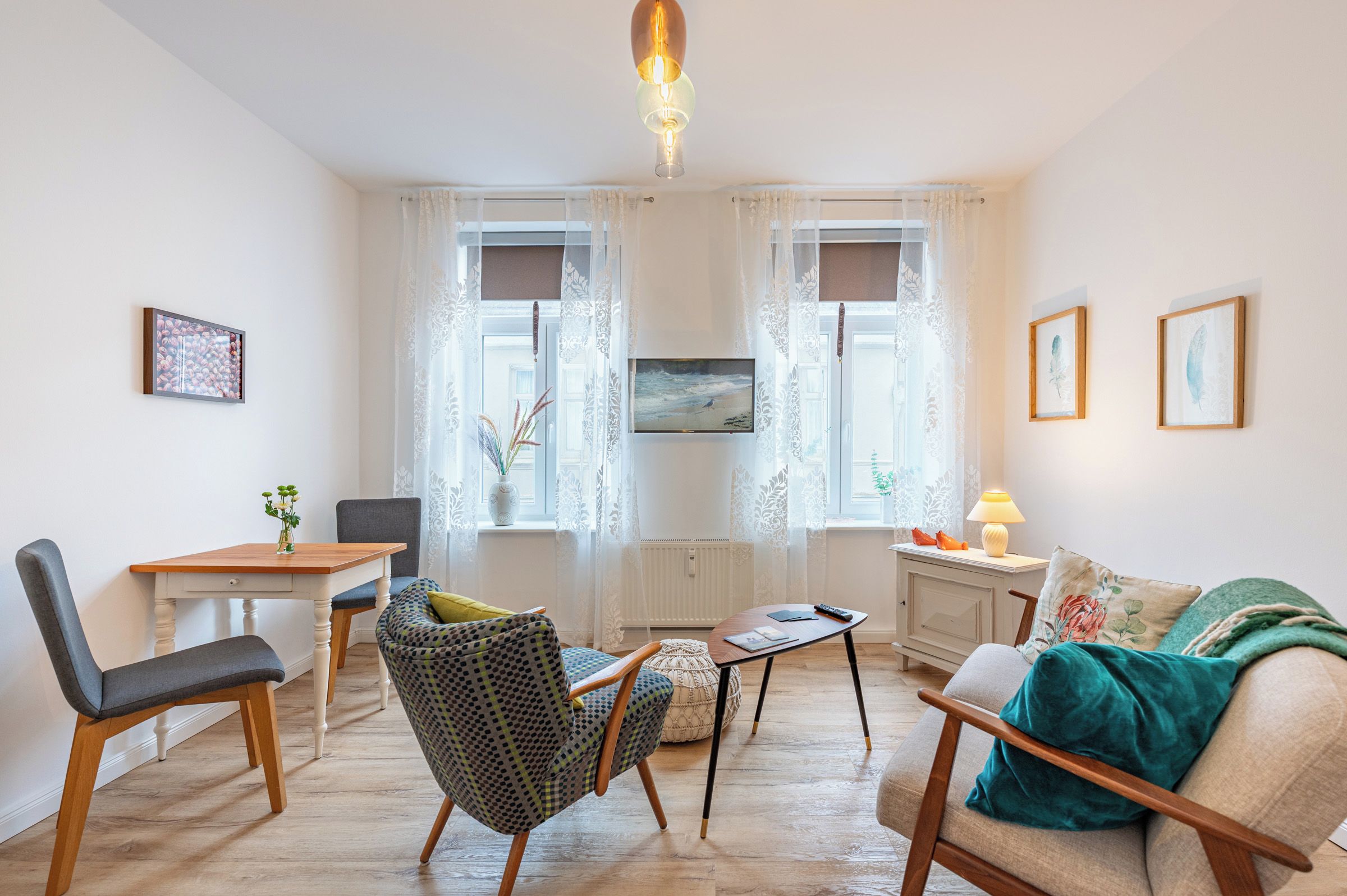 Ein Wohnzimmer mit Esstisch, zwei Stühlen, einer Couch, einem Couchtisch und einer Lampe.