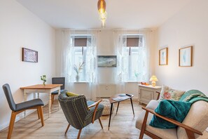 A living room with a dining table, two chairs, a sofa, a coffee table, and a lamp.