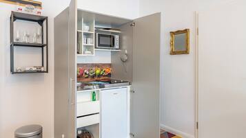 Una cocina compacta con microondas, refrigerador pequeño y lavamanos.