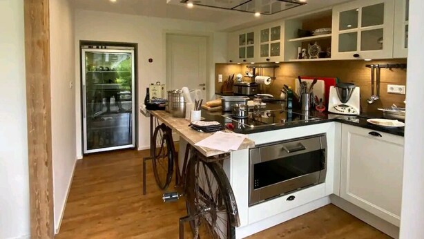 Una cocina moderna con armarios blancos, una isla central y suelo de madera.