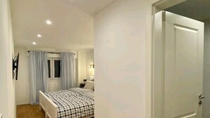 Un dormitorio con cama, puerta y ventana con cortinas.