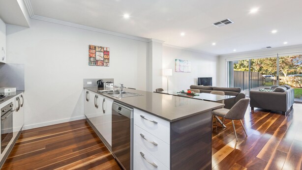 A modern kitchen with a central island, stainless steel appliances, and a dining area with a sofa and table.
