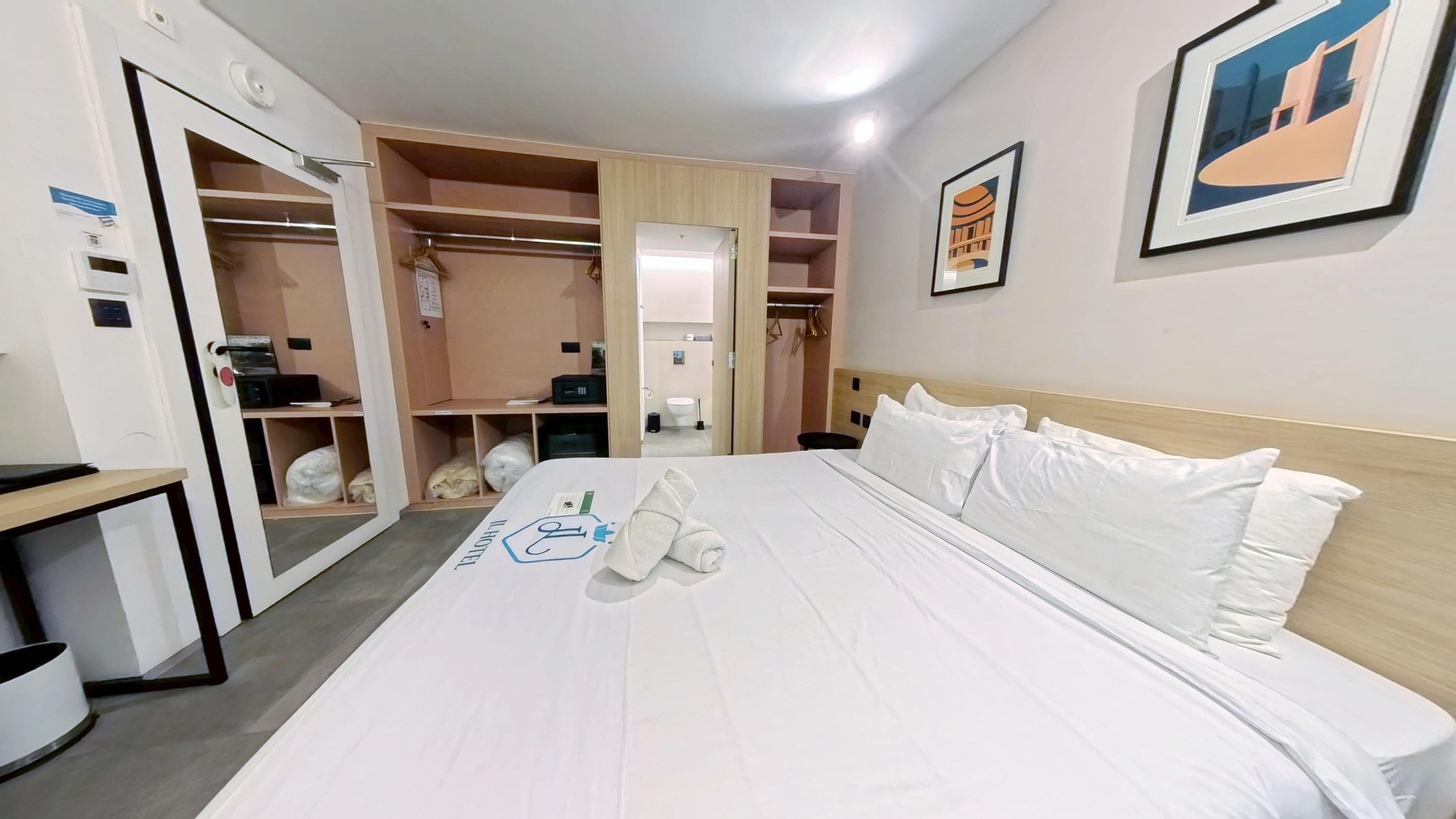 A hotel room with a bed, a desk, and a wardrobe.
