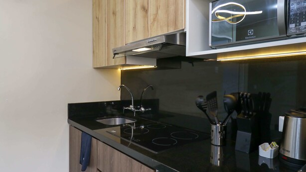 A modern kitchen with a black countertop, stainless steel appliances, and wooden cabinets.