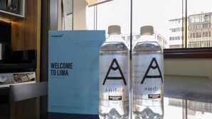 A welcome sign and two water bottles with 'A' labels on a reflective surface.