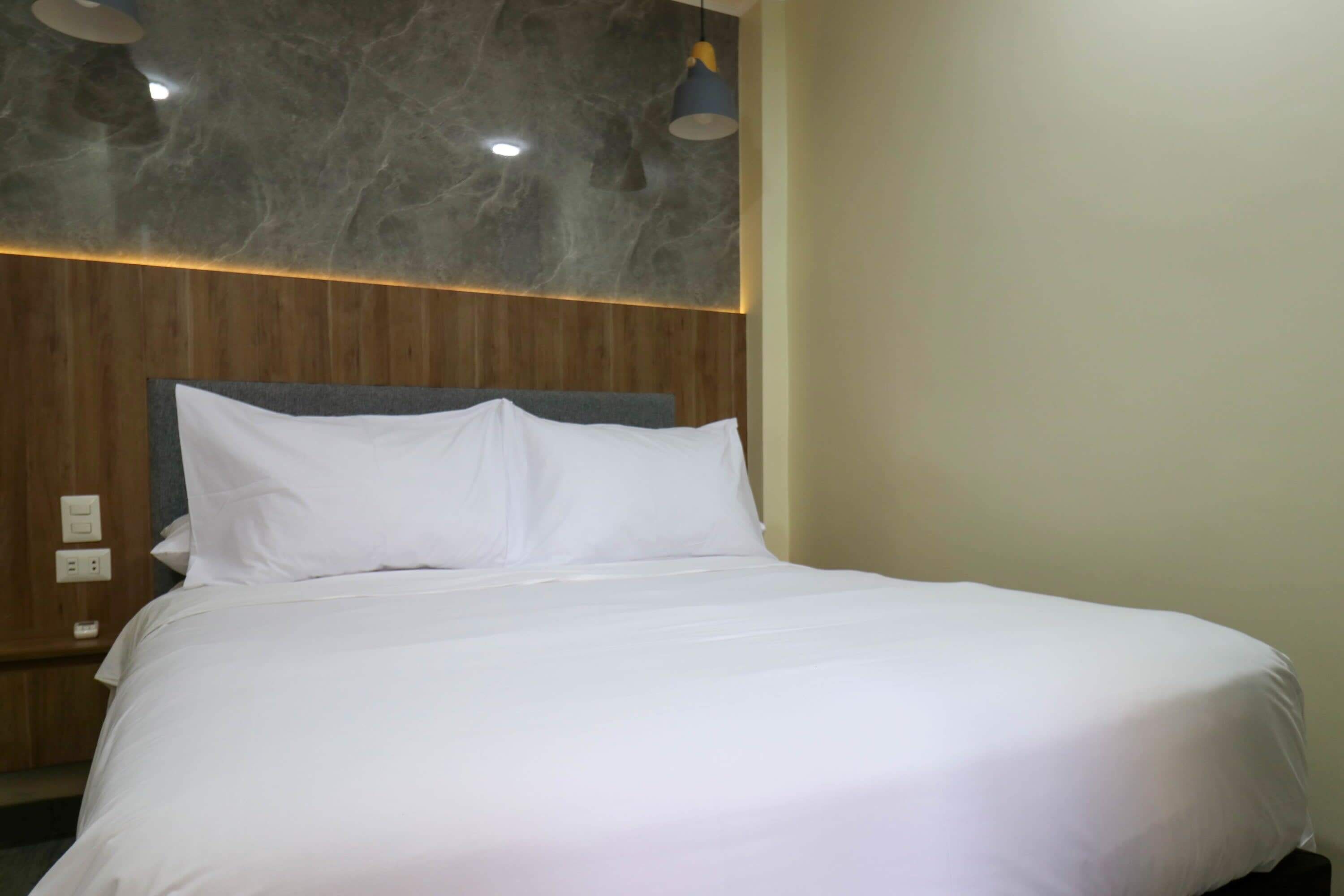 Ein ordentlich bezogenes Bett mit weißen Laken in einem Hotelzimmer.