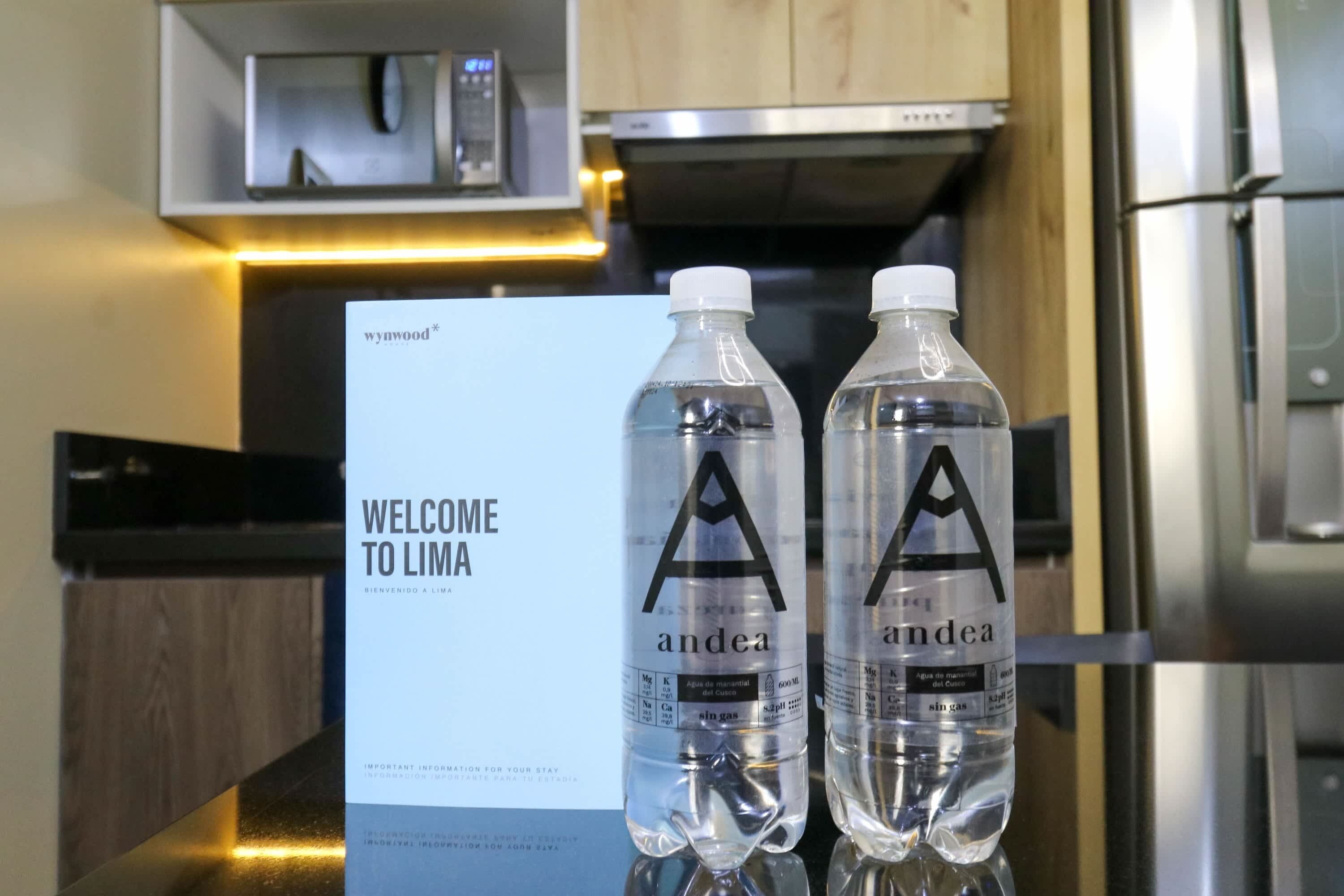 Twee flessen water met de aanduiding 'andea' op een toonbank, naast een bord met de tekst 'Lima'.