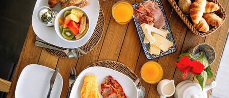 A breakfast table with croissants, cheese, ham, and fruit.