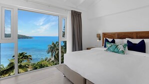 A bedroom with a large window overlooking a beach and ocean. - The Bay Seychelles Boutique Hotel and Apartments (Mahé Island)