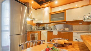 A modern kitchen with stainless steel appliances, wooden cabinets, and a dining area with a table set for two. - Residenza Dolce Lago (Como)