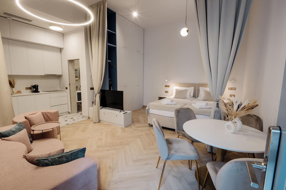 Una habitación de hotel moderna con sofá, mesa de comedor y televisor.