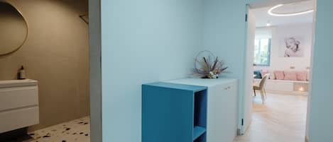 Een moderne badkamer met een wit wastafelmeubel, een ronde spiegel en een vloer met stippen.
