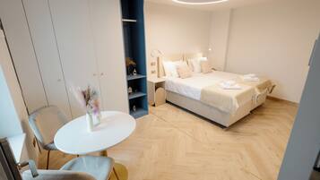 A modern hotel room with a bed, bedside tables, a round table, and a chair.